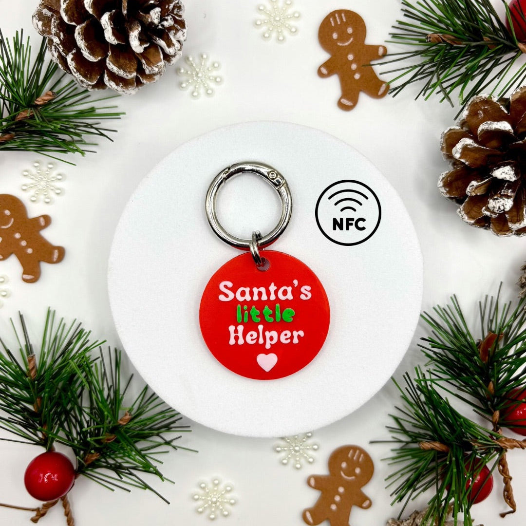 Keychain with 'Santa's little Helper' text on a white background with Christmas decorations.