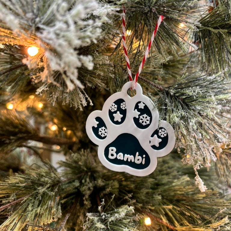 Decorative paw print ornament with 'Bambi' on a Christmas tree.